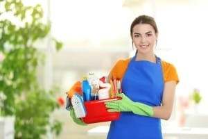 Green Cleaning Services - Woman in rubber gloves holding basin with detergents on blurred background