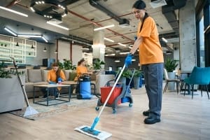 Kelowna janitorial services - Three uniformed ladies cleaning lobby wearing orange shirts - Evergreen Building Maintenance Inc. commercial cleaning and janitorial services.