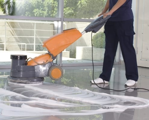 Kamloops office cleaning services - partial body of person using an orange floor polishing machine