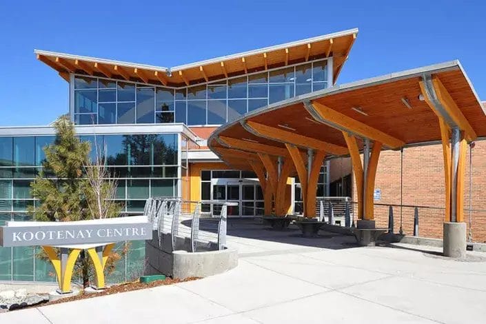 Modern building with large windows, wooden beams, and an overhanging roof. A sign reading "Kootenay Centre" stands in front. The sky is clear and blue—ideal for showcasing expert property maintenance and janitorial cleaning services.