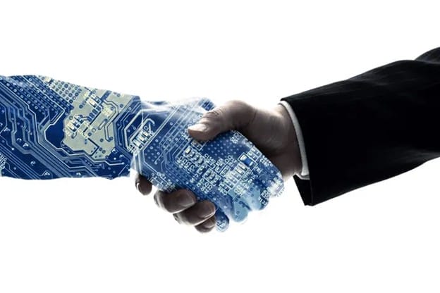 A human hand in a business suit shakes hands with a robotic hand made of blue computer circuitry, symbolizing partnership between technology and humans.